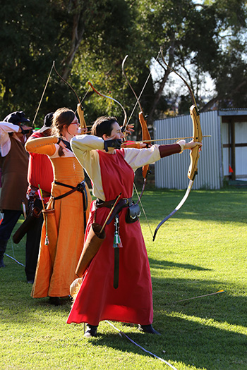 Archery with people in a row ion the shooting line.